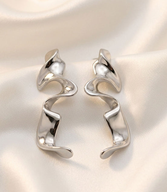 Boucles d’oreilles argentées sculpturales au design ondulé moderne.