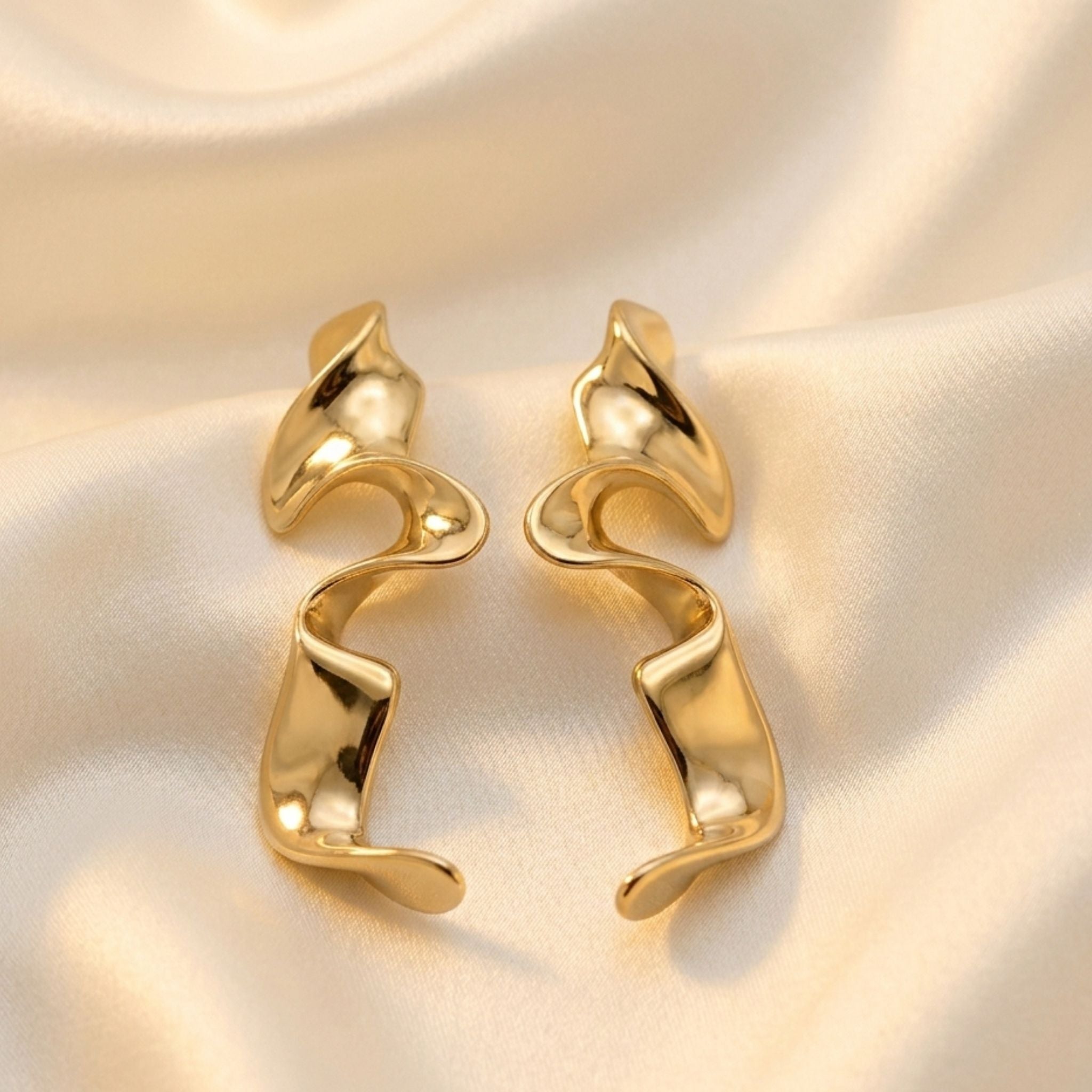 Boucles d’oreilles argentées sculpturales au design ondulé moderne.