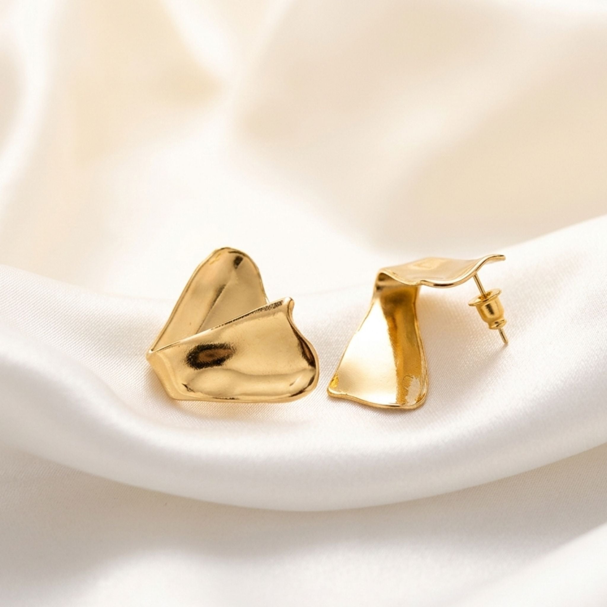 Boucles d’oreilles dorées sculpturales finition brillante.