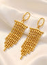 Boucles d’oreilles dorées longues à perles en cascade.