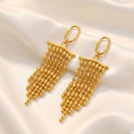 Boucles d’oreilles dorées longues à perles en cascade.