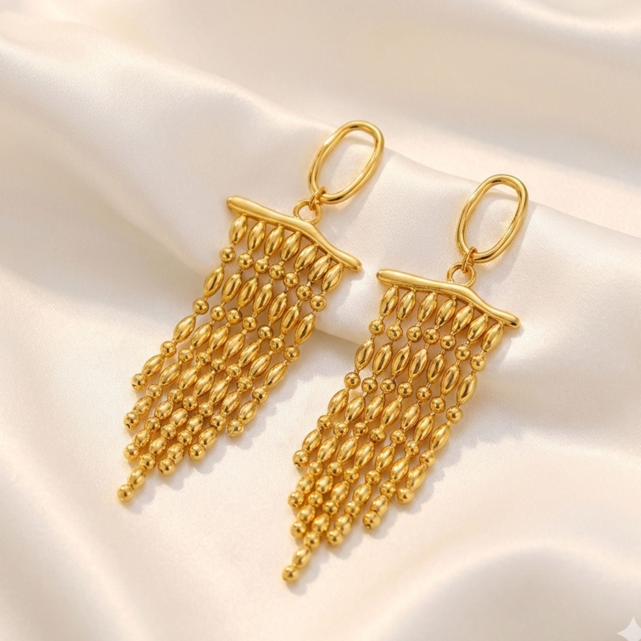 Boucles d’oreilles dorées longues à perles en cascade.