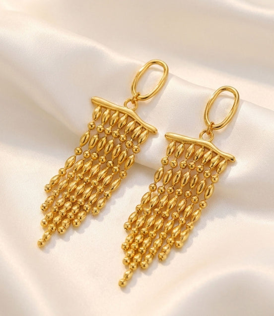 Boucles d’oreilles dorées longues à perles en cascade.