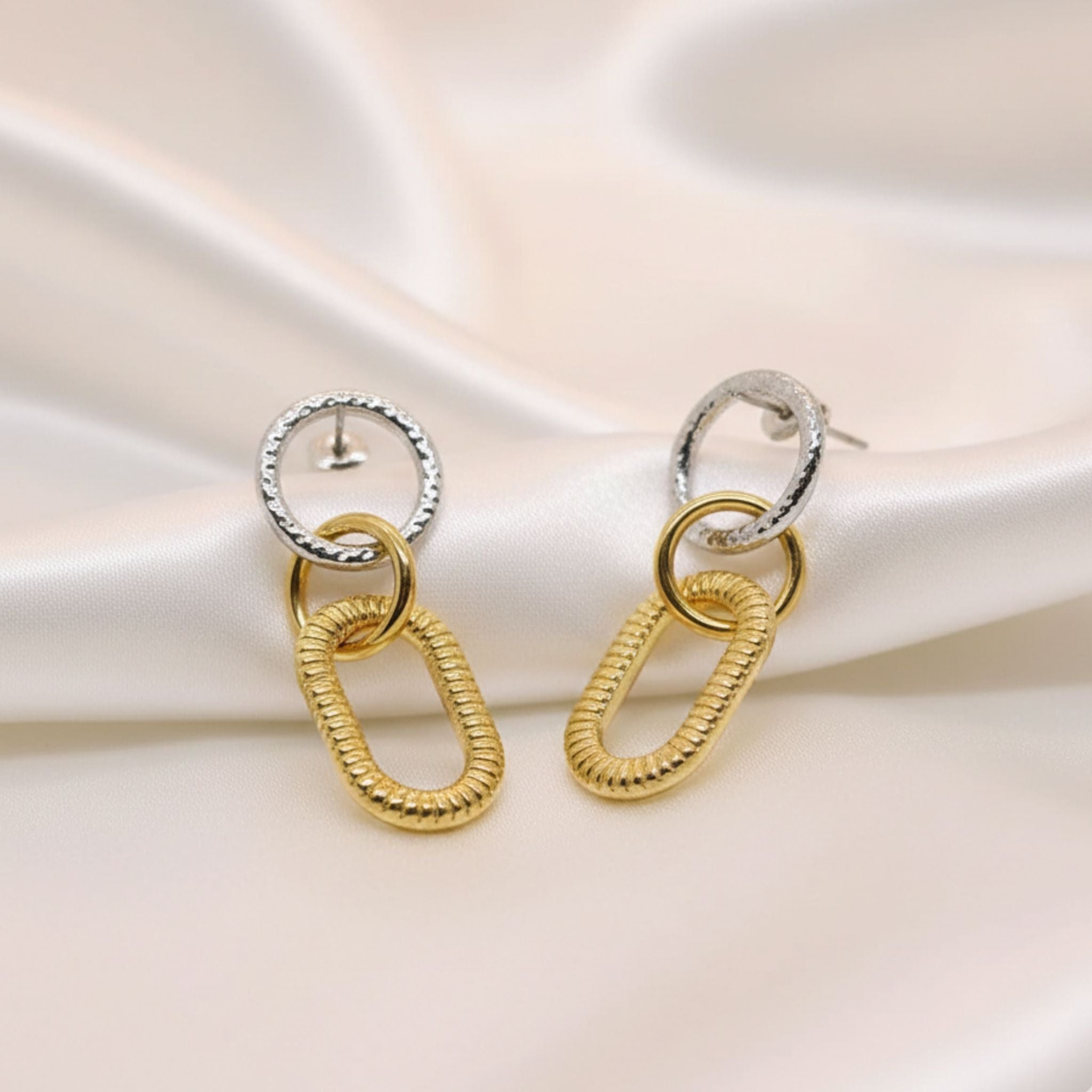 Boucles d’oreilles pendantes bicolores avec maillons dorés texturés.