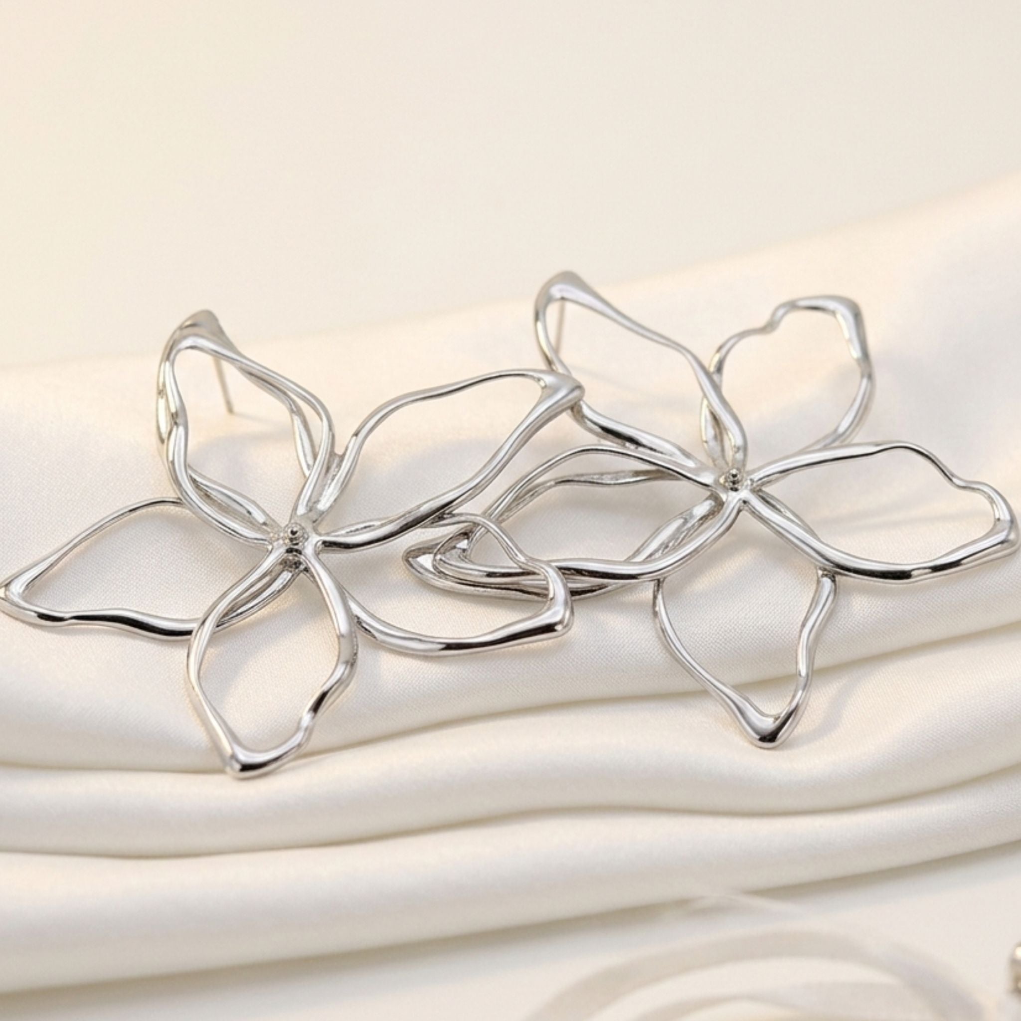 Boucles d’oreilles fleurs argentées ajourées effet miroir.