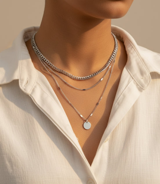 Superposition de chaînes argentées élégantes sur présentoir blanc